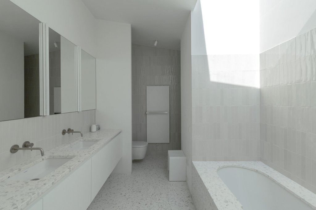 Badkamer met lavabo en badomranding uit natuursteen terrazzo bomarbre multicolor pastel.